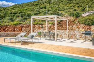 a patio with a table and chairs next to a pool at Villa Iliotropos in Spathíon