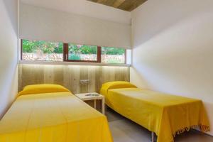 サン・リュイスにあるVilla Ullastres Ses Alzinesの黄色のシーツと窓が備わる客室のベッド2台分です。 +8枚の写真