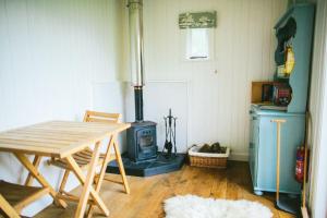 um quarto com uma mesa de madeira e um fogão em Snowdonia Shepherds' Huts em Conwy