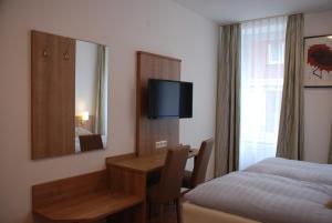 una camera d'albergo con letto, scrivania e specchio di Hotel Rest Inn a Bretten