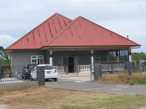 a building with a red roof with a car parked in front at Chander's Villa in Paramaribo