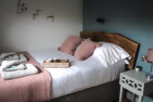 a bedroom with a bed with white sheets and pink pillows at Cwm Heulog in Knighton