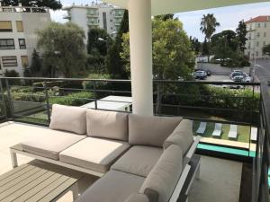 um sofá branco sentado em cima de uma varanda em Appartement montfleury, 2 terrasses, 2 chambres , 2 sdb , pkg privé piscine, 15 min walk to Croisette beach and Palais des festivals em Cannes