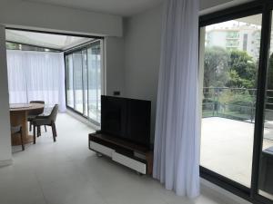 a living room with a tv and a large window at Appartement montfleury, 2 terrasses, 2 chambres , 2 sdb , pkg privé piscine, 15 min walk to Croisette beach and Palais des festivals in Cannes