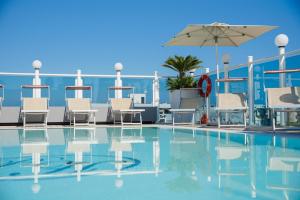 einen Pool mit Stühlen und einem Sonnenschirm in der Unterkunft Hotel President in Rimini
