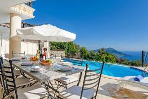 a table with chairs and an umbrella next to a pool at Villa Azalea in Kalkan