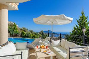 a patio with a couch and an umbrella next to a pool at Villa Azalea in Kalkan