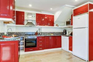 a red kitchen with white appliances and red cabinets at Villa Azalea in Kalkan