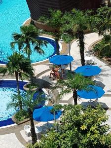 uma vista sobre uma piscina com guarda-sóis azuis e palmeiras em Ts service suites at Times Square em Kuala Lumpur