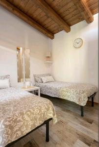 two beds in a room with a clock on the wall at Maison Champagne in Camino