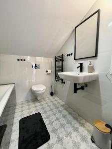 La salle de bains blanche est pourvue d'un lavabo et de toilettes. dans l'établissement Apartament za Ratuszem - z balkonem, à Radom
