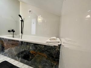 La salle de bains est pourvue d'une baignoire, d'un lavabo et de serviettes. dans l'établissement Apartament za Ratuszem - z balkonem, à Radom