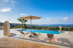uma piscina com uma mesa e cadeiras e um guarda-sol em Villa Blue Jadeite em Kissonerga