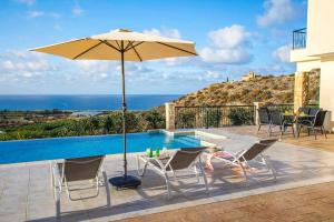 um pátio com um guarda-sol e cadeiras e uma piscina em Villa Blue Jadeite em Kissonerga