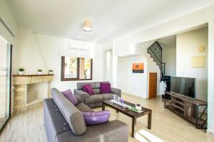 uma sala de estar com um sofá e uma televisão em Villa Blue Jadeite em Kissonerga
