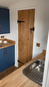 a kitchen with a sink and a wooden door at Wren - Luxury Shepherd's Hut with Hot Tub in Manea