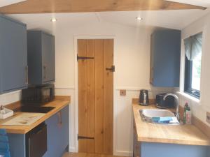 a kitchen with a sink and a wooden door at Wren - Luxury Shepherd's Hut with Hot Tub in Manea