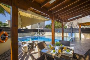a patio with a table and chairs next to a swimming pool at Tropical Beach Villa in Ayia Napa
