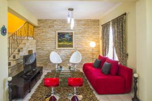 a living room with a red couch and red chairs at Tropical Beach Villa in Ayia Napa