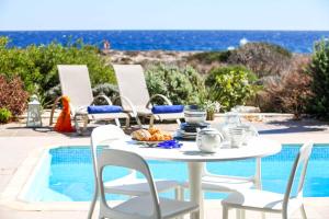 einen weißen Tisch und Stühle neben einem Pool in der Unterkunft Villa Melissa Selana in Protaras