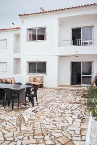 a patio with a table and chairs and a building at Baleal Surf Emotions in Baleal