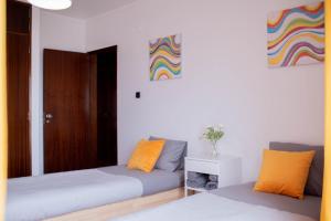 a bedroom with two beds and a colorful painting on the wall at Baleal Surf Emotions in Baleal