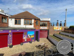 ein Haus mit roten Garagentüren davor in der Unterkunft Coral Beach - Row 73 Van 2, central heating, WiFi, bed linen - Meadow Lakes Caravan & Lodge Hire in Ingoldmells