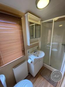 ein Badezimmer mit einem weißen Waschbecken und einer Dusche in der Unterkunft Coral Beach - Row 73 Van 2, central heating, WiFi, bed linen - Meadow Lakes Caravan & Lodge Hire in Ingoldmells
