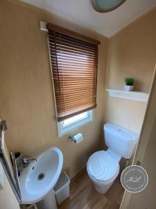 ein Badezimmer mit Toilette und Waschbecken und einem Fenster in der Unterkunft Coral Beach - Row 73 Van 2, central heating, WiFi, bed linen - Meadow Lakes Caravan & Lodge Hire in Ingoldmells