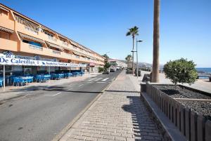 une rue vide avec un bâtiment et un palmier dans l'établissement Chipaz Candelaria, à Santa Cruz de Tenerife