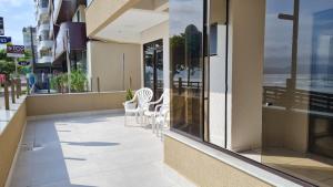 ein Gebäude mit Stühlen und Tischen auf einem Gehweg in der Unterkunft Apto pé na areia em Meia Praia Itapema, 3 dormitórios in Itapema