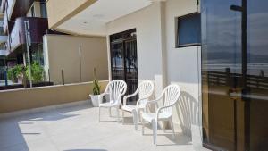 un grupo de sillas blancas sentadas en un balcón en Apto pé na areia em Meia Praia Itapema, 3 dormitórios, en Itapema