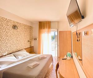 a hotel room with a bed and a television at Hotel Ravello Adults Only in Rimini