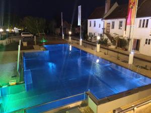 a large blue swimming pool at night at Das-Schmidt Privathotel in Mörbisch am See