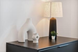 a table with two white vases and a lamp on it at Center Wien designer central modern apartment in Vienna