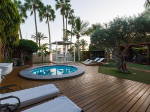 une terrasse en bois avec une piscine et des palmiers dans l'établissement Villa Kai by Maspalomas Holiday Villas, à Pasito Blanco