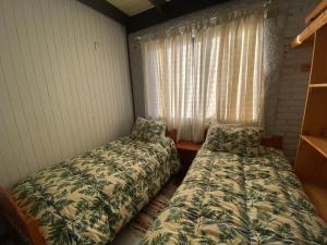 two beds in a room with a window at Cabañas Patagonia LicanRay in Licán Ray