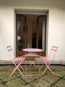 een roze tafel en twee stoelen voor een gebouw bij Hyper centre Deauville in Deauville