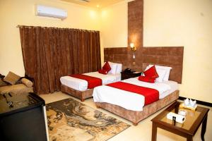 a hotel room with two beds and a television at Shelton Residency Lahore in Lahore