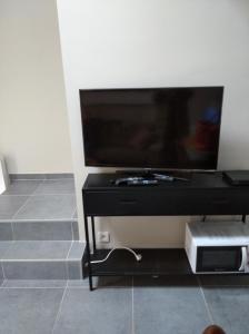 een flatscreen-tv zittend op een zwarte standaard bij Terrasses de Malmedy Lodge 417 in Malmedy