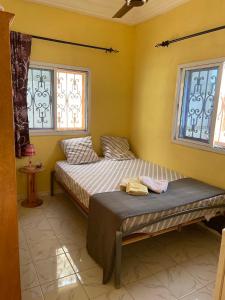 a bedroom with two beds and two windows at The Compound in Bijilo