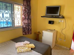 ein Schlafzimmer mit einem Bett und einem Fernseher an der Wand in der Unterkunft The Compound in Bijilo