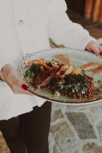 a woman holding a plate of food on a plate at Bajka Hotel & Resort in Grodziec