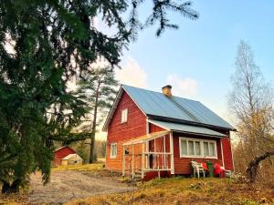 uma casa vermelha com um telhado de metal e duas cadeiras em Finnish house near the forest em Lappeenranta