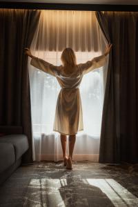 Bajka Hotel & Resort في Grodziec: امرأة تقف أمام النافذة