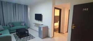 Amman La Maison Hotel Suites في عمّان: غرفة معيشة بها أريكة خضراء وتلفزيون