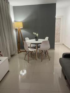 a living room with a table and white chairs at Apartamento ao Lado do Centro de Convenções do Rio Centro! 8 min da praia do Recreio dos Bandeirantes in Rio de Janeiro
