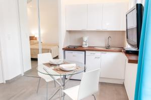 a small kitchen with a glass table and white chairs at Domaine équestre de la Chênaie in Saumur