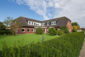 a large brick house with a green yard at Hotel Villa Norderney in Neßmersiel