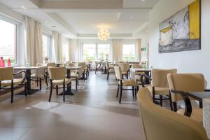 una sala da pranzo con tavoli, sedie e finestre di Hotel Villa Norderney a Nessmersiel
